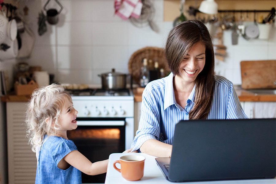 Blog - Mother and Young Child in the Kitchen While Mom is Working on Her Laptop