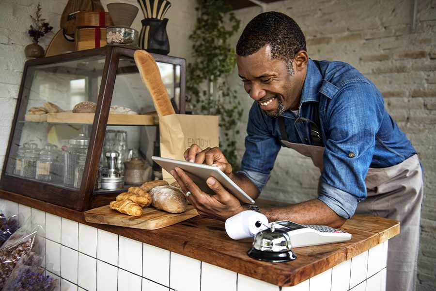 Business Insurance - Business Employee Working at a Counter in a Small Bakery and Using a Tablet