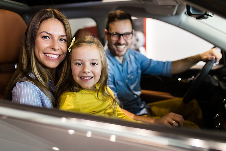 Personal Insurance - Happy Family Sitting in New Vehicle and Getting Ready to Drive Out of the Dealership